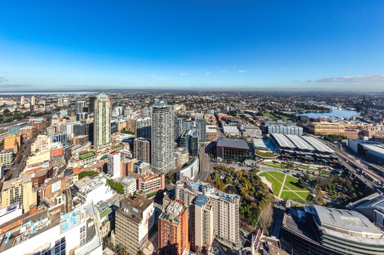 Meriton Suites Kent Street, Sydney Exterior photo The photo captures a panoramic view of a city skyline. It showcases a mix of modern high-rise buildings and urban structures. There's a notable park area with greenery, interspersed with roads and pathways. The layout suggests a vibrant urban environ